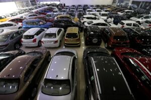 FILE PHOTO: Auto dealers stand between the cars displayed for sale at a second hand car showroom Shoneez Motors in Sanabis, west of Manama